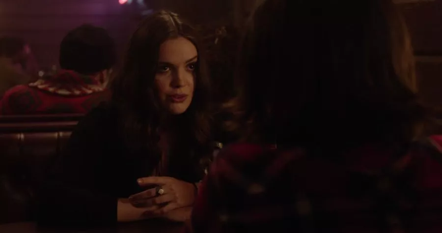 Megan sits at a bar booth, explaining a complicated story with her hands clasped in front of her.