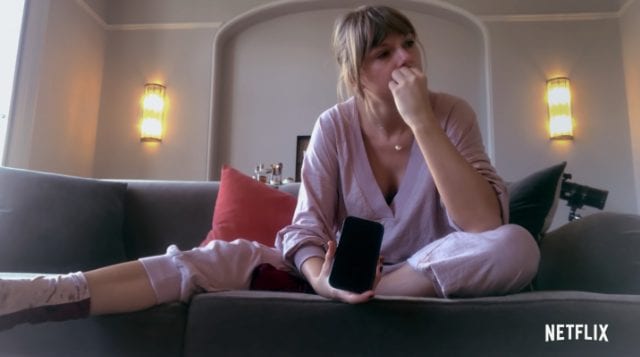 Taylor Swift crying on her sofa with her phone in her hand