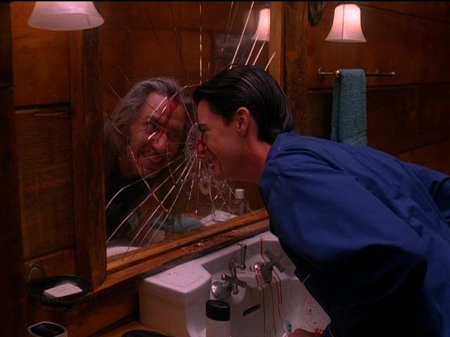 Image of Dale Cooper smashing his face into the mirror and grinning maniacally while staring at BOB in his reflection. Blood streams down his forehead and onto the bathroom sink.