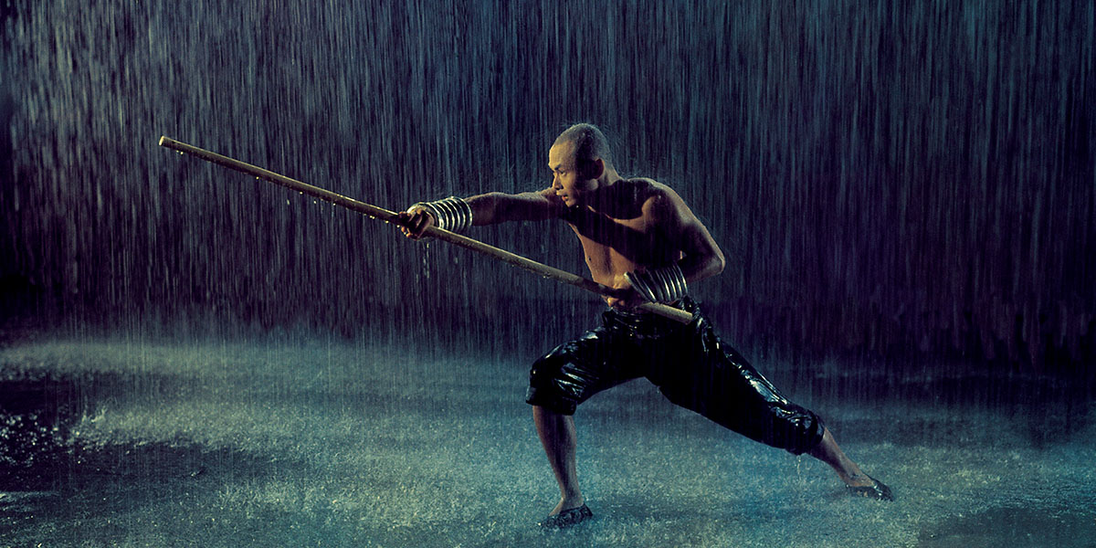 Gordon Liu lunges with a staff in the rain