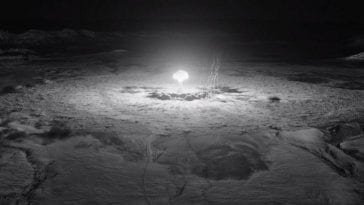 A black and white look at a nuclear mushroom cloud explosion from extremely far away.