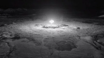 A black and white look at a nuclear mushroom cloud explosion from extremely far away.