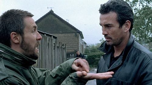 Richard stands with his hand open and finger pointing to it as Sonny watches on.
