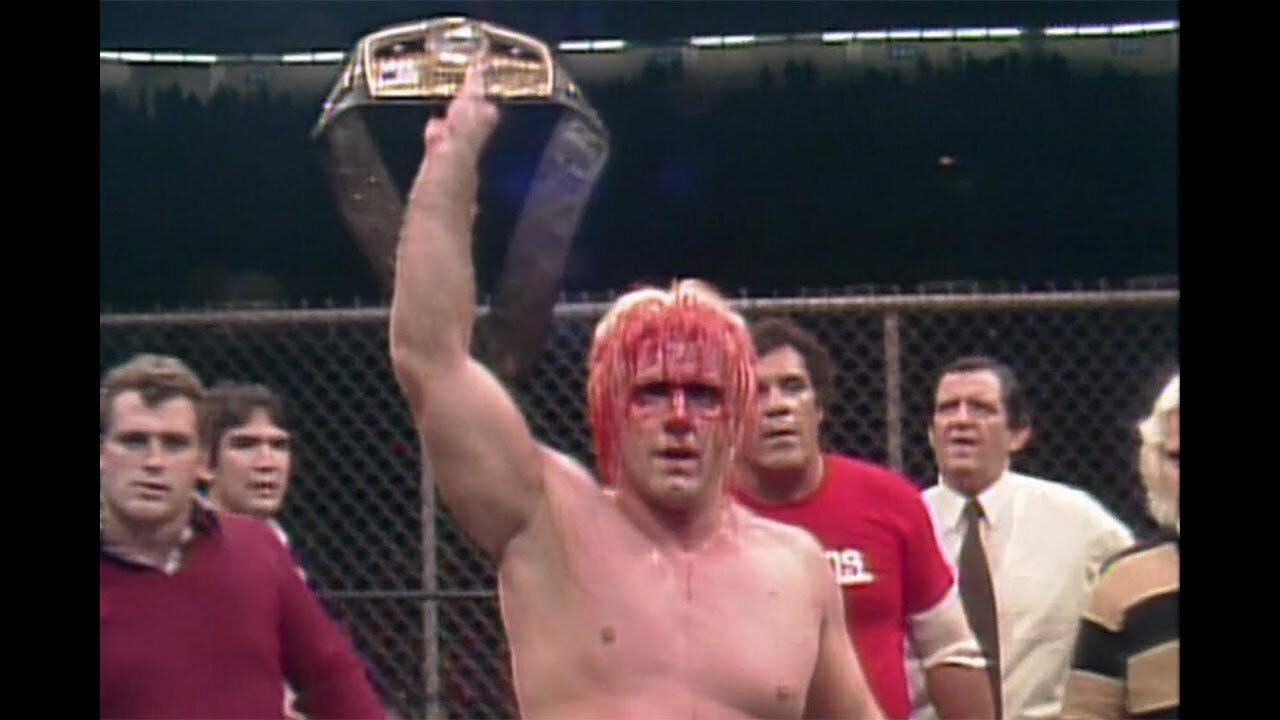 A bloody Ric Flair holds up the Ten Pounds of Gold at Starrcade 1983