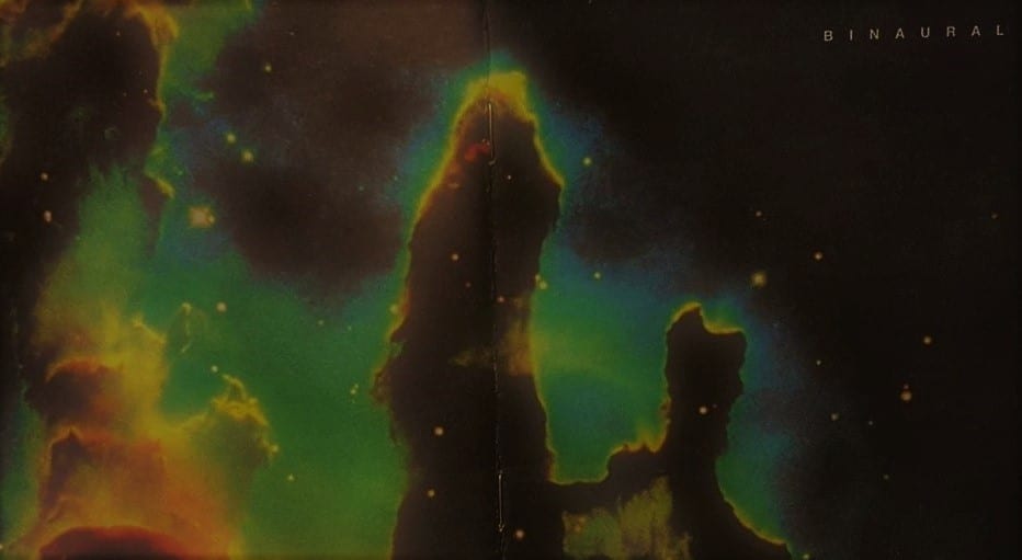 A cluster of yellow stars, surrounded by dark column shapes that are encased in a greenish/blue aura.