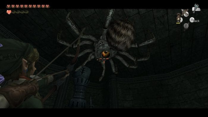 Link lines up a shot at a giant spider crawling on the ceiling
