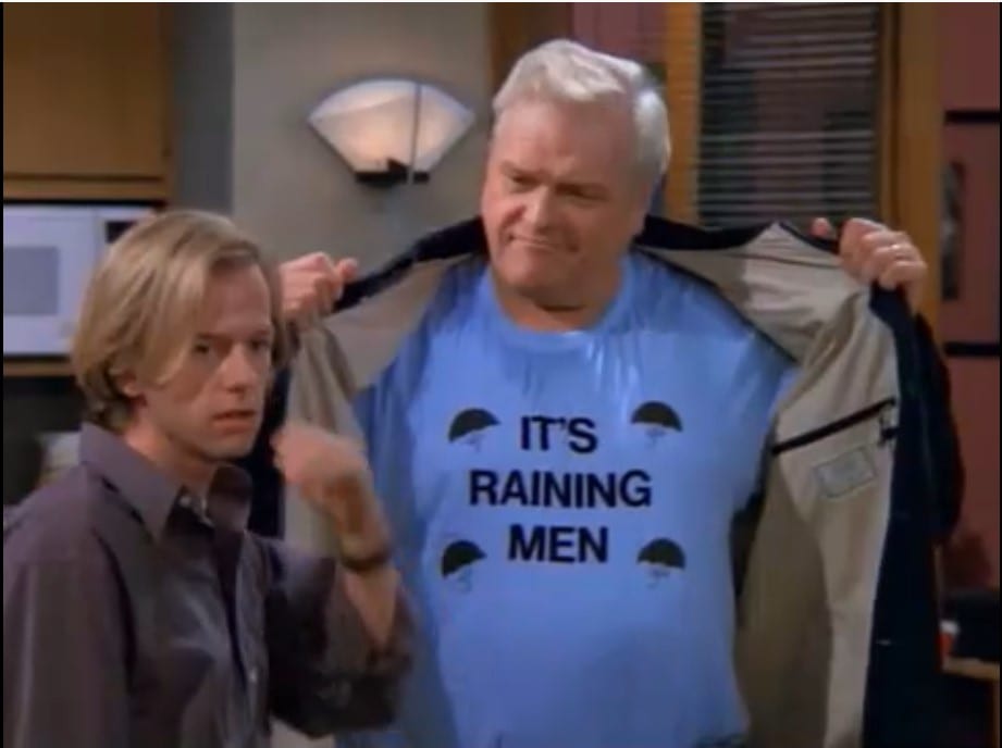 Dennis stands next to his father who holds open his jacket to reveal a shirt that says "It's Raining Men"