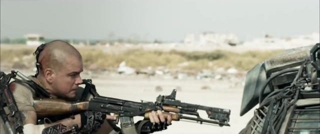 Max Da Costa stands in cover behind a car with a modified AK-47 drawn