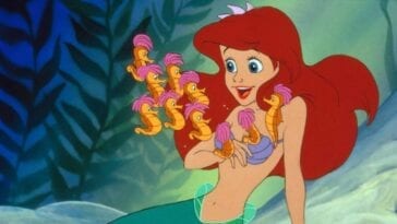 Ariel happily watches a bunch of seahorses swimming around her