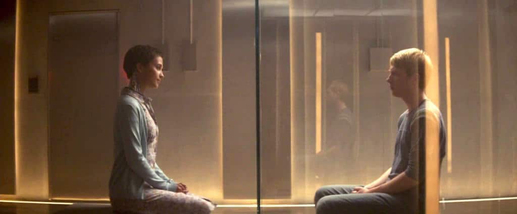 Ava and Caleb sit on their knees, either side of the glass room during one of their sessions