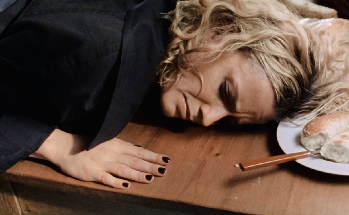 Sera bends over a table with a frightened look