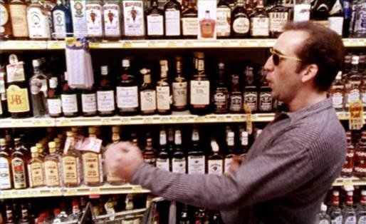Nic Cage as Ben dancing as he adds bottles of alcohol into his shopping cart