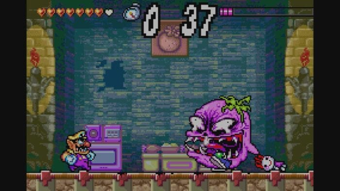 Wario confronts Spoiled Rotten, the first boss of Wario Land 4, which looks like a giant grape with sneakers and teeth