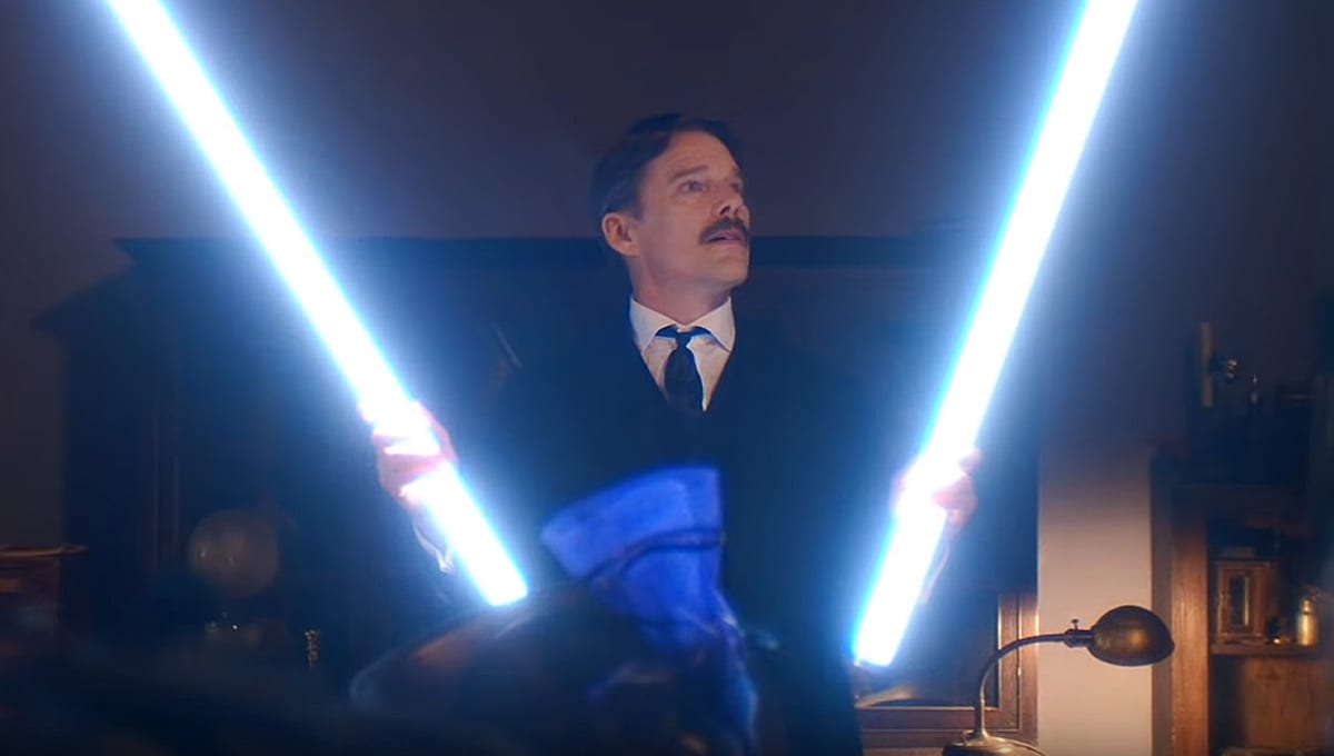 Nikola Tesla (Ethan Hawke) holds up two long light sticks, admiring them.