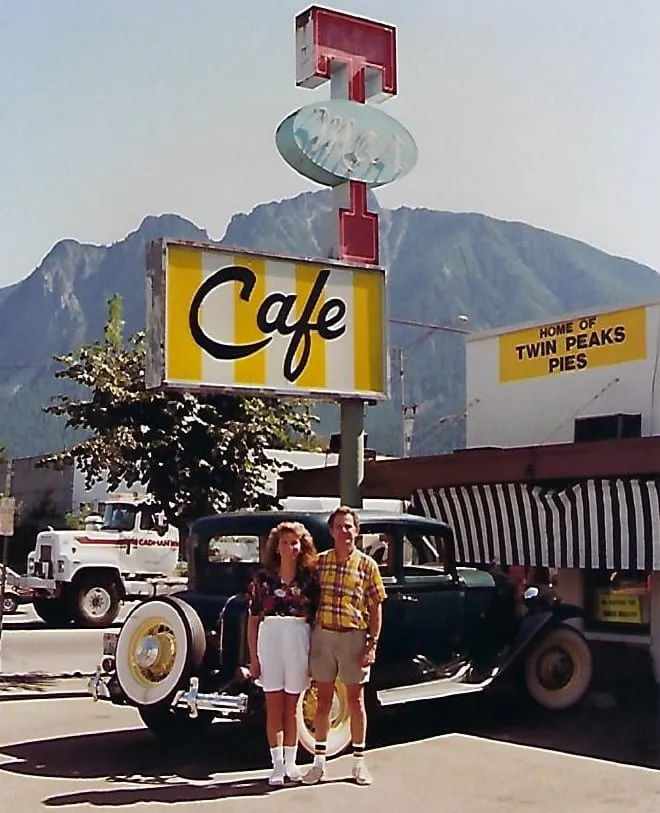 two people standing in front of a classic car, parked by the classic Double R sign at Twede's Cafe.