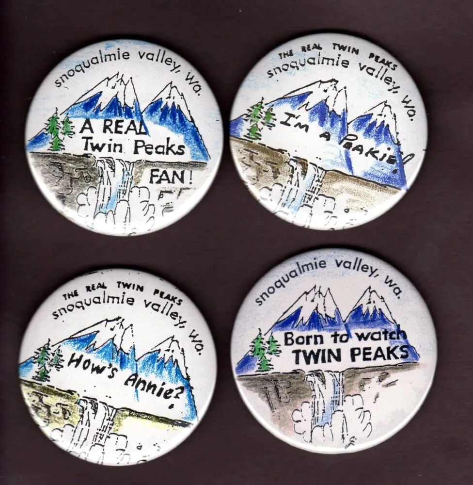 handmade Twin Peaks buttons, painted mountains with writing on them.