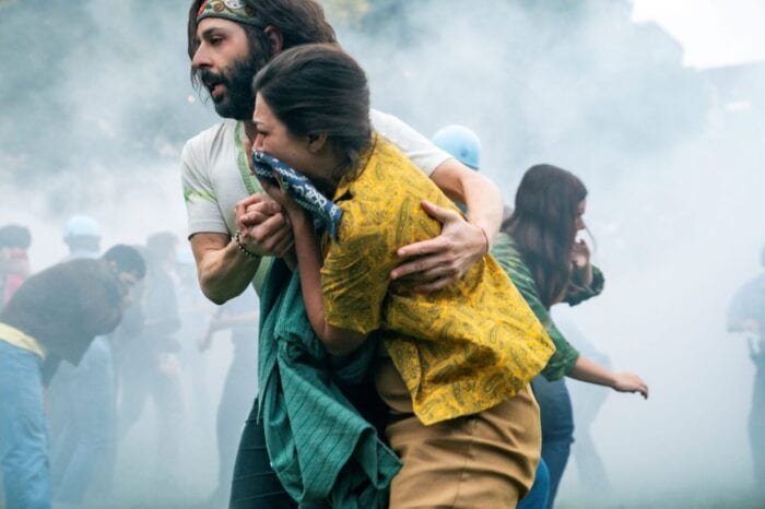 Jerry Rubin tries to lead a woman to safety through tear gas.