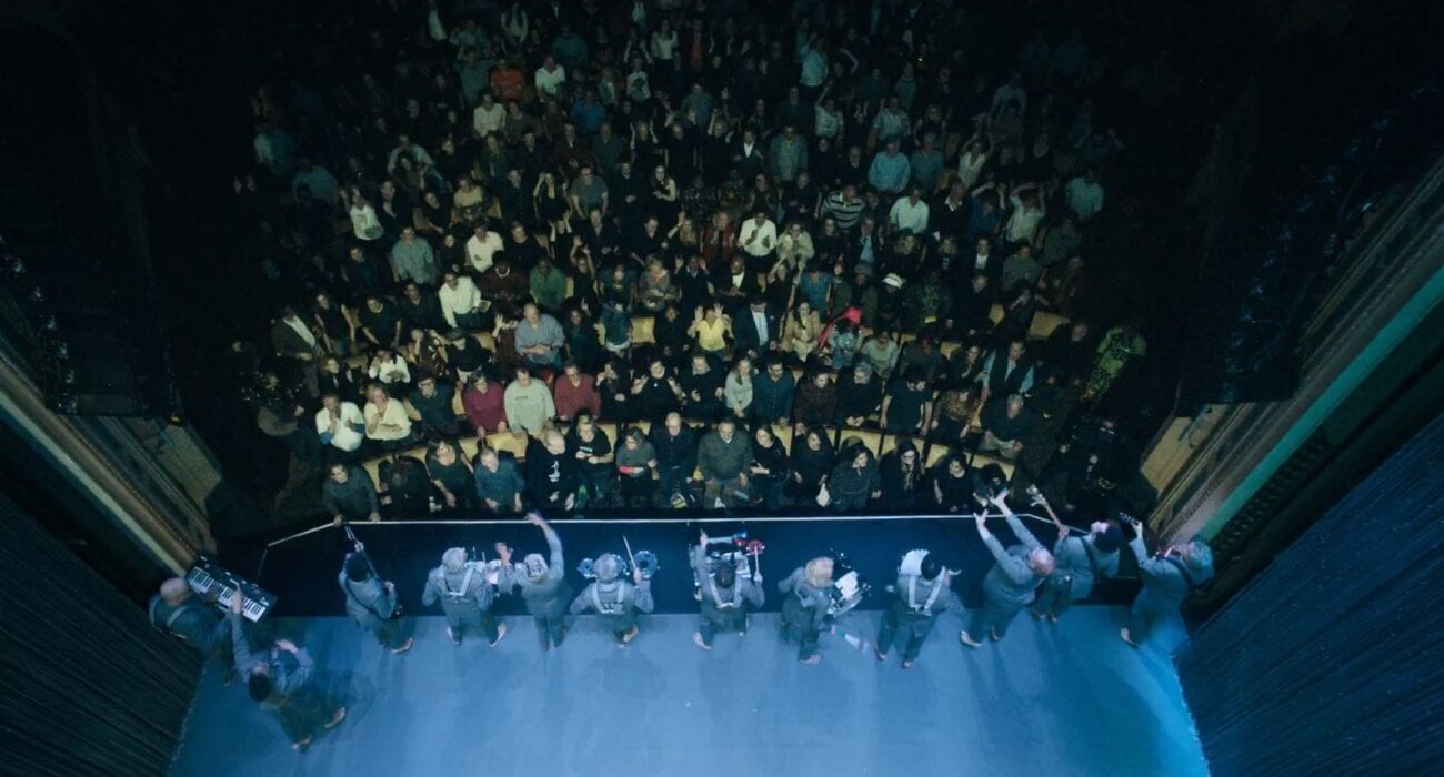 The cast of American Utopia stand at the edge of the stage at the end of "Burning Down The House." Byrne is standing stage right. "God's eye" overhead shot.