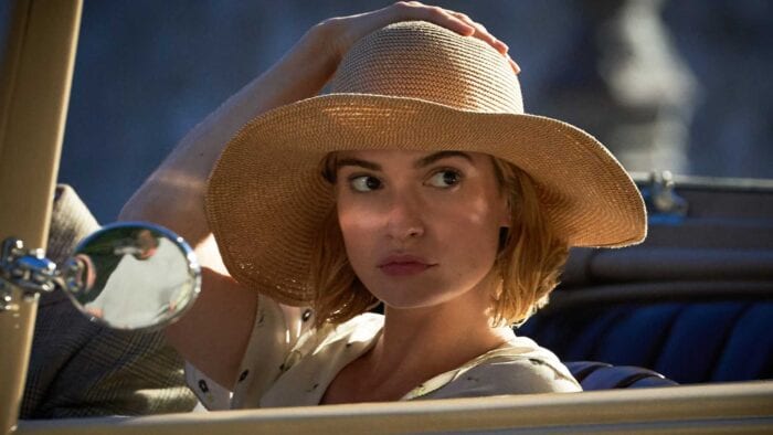 The future Mrs. de Winter gazes over at Maxim from a car while clutching her hat.