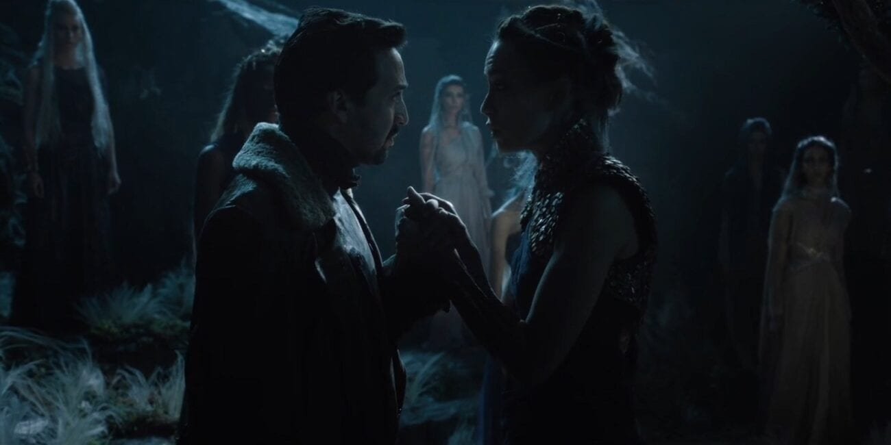 His Dark Materials - Lee and Serafina clasp hands facing each other as several other witches look on