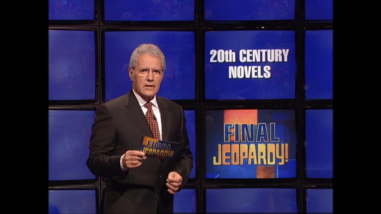 Ale Trebek stands in front of a Final Jeopardy! board with a category that reads 20th Century Novels