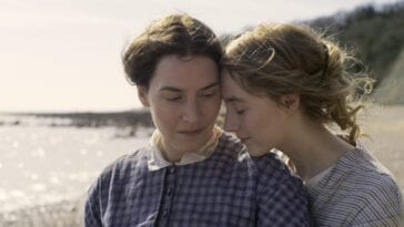 Charlotte (Saoirse Ronan) snuggles up to Mary(Kate Winslet) on the Beach in a still from "Ammonite"