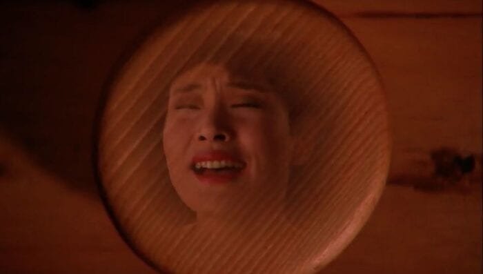 Josie's face is imprisoned in the knob of a wooden drawer.