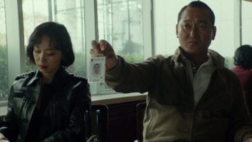 A woman in a leather jacket and a man holding an ID badge sit in a café in Beasts Clawing at Straws.