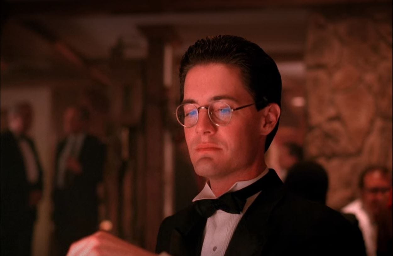 Dale Cooper wears glasses, a suit and a bowtie as he sits gambling at One-Eyed Jacks