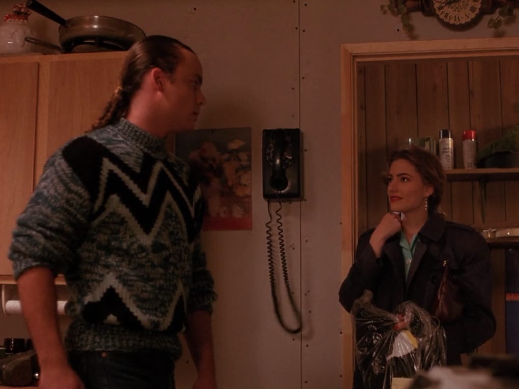 Leo and Shelly Johnson exchange looks in front of a mounted print of a poodle on the set of Twin Peaks.