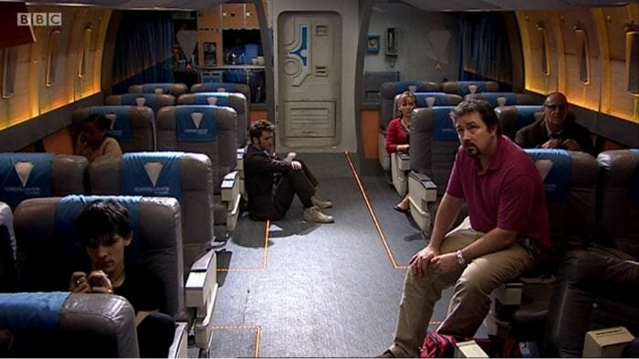 Every passenger on the bus sits in separate areas, the Doctor slouched in the aisle.