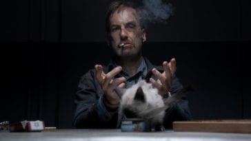 Hutch lets go of a cat to step forward and eat while he is handcuffed and smoking a cigarette.