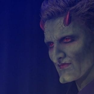 Lorne (green skin, little red horns, red eyes, snazzy suit) on stage in his first appearance in 'Judgement'