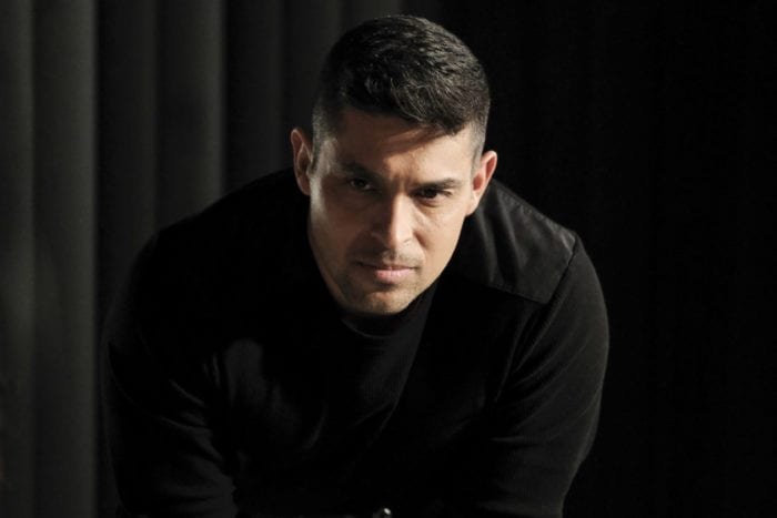 NCIS Agent Nick Torres (Wilmer Valderrama) leans seriously over a table