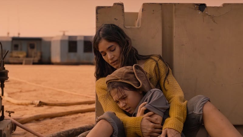 In Settlers, Isla (Sofia Boutella) cradles a young Remmy (Brooklyn Prince). 