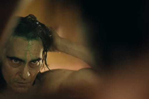 Joker washes the green out of his hair in front of a mirror