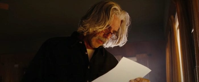 Lorne Lutch (Sam Elliott) reads a piece of paper in a dark room