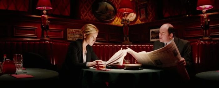 Polly (Maria Bello) and Bobby (David Koechner) read newspapers in the corner of a dimly lit bar