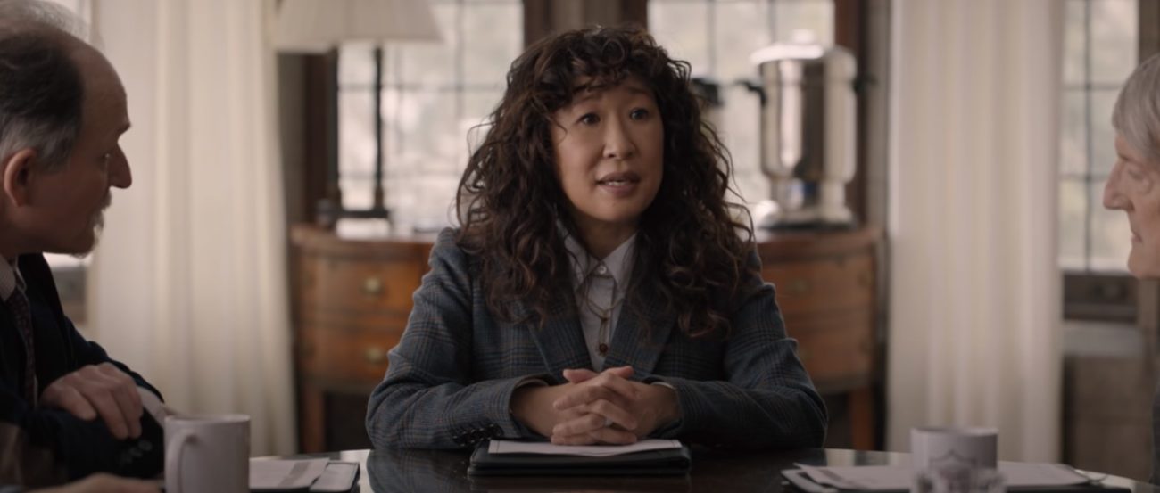 Professor Ji-Yoon Kim (Sandra Oh) sits at the head of a conference table with windows behind her and two people on the edges of the frame
