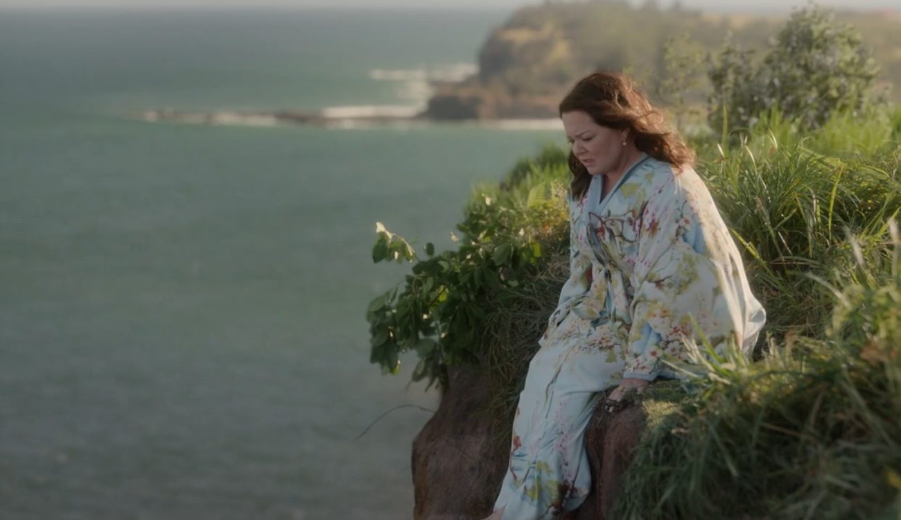 Frances (Melissa McCarthy) sits on the edge of a cliff overlooking the ocean.