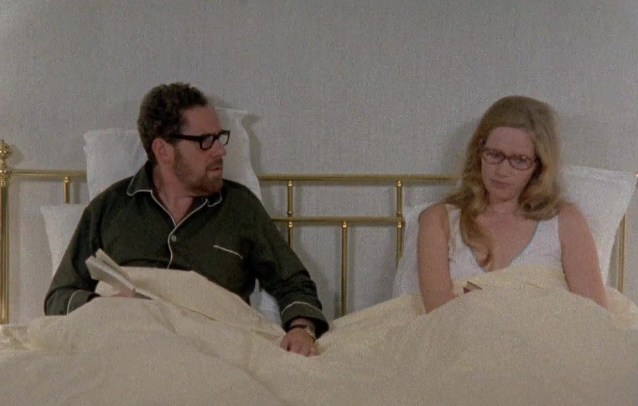 In this image from Ingmar Bergman's 1973 series Scenes from a Marriage, the characters Johan (Erland Josephson) and Marianne (Liv Ullman) are depicted together sitting in bed in their pajamas and reading glasses.