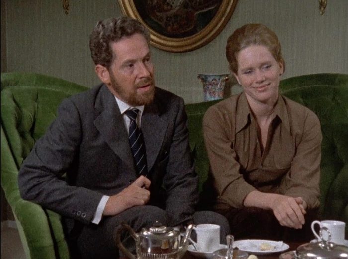 In this image from Ingmar Bergman's Scenes from a Marriage, Johan (Erland Josephson) and Marianne (Liv Ullman) are depicted in a living room setting sitting together on a loveseat.