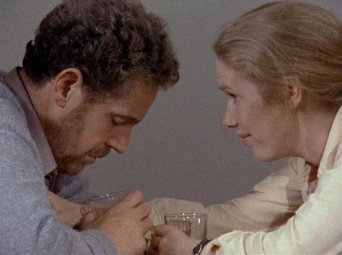 In this image from Scenes from a Marriage, the characters Johan (Erland Josephson) and Marianne (Liv Ullman) embrace each other over a table.