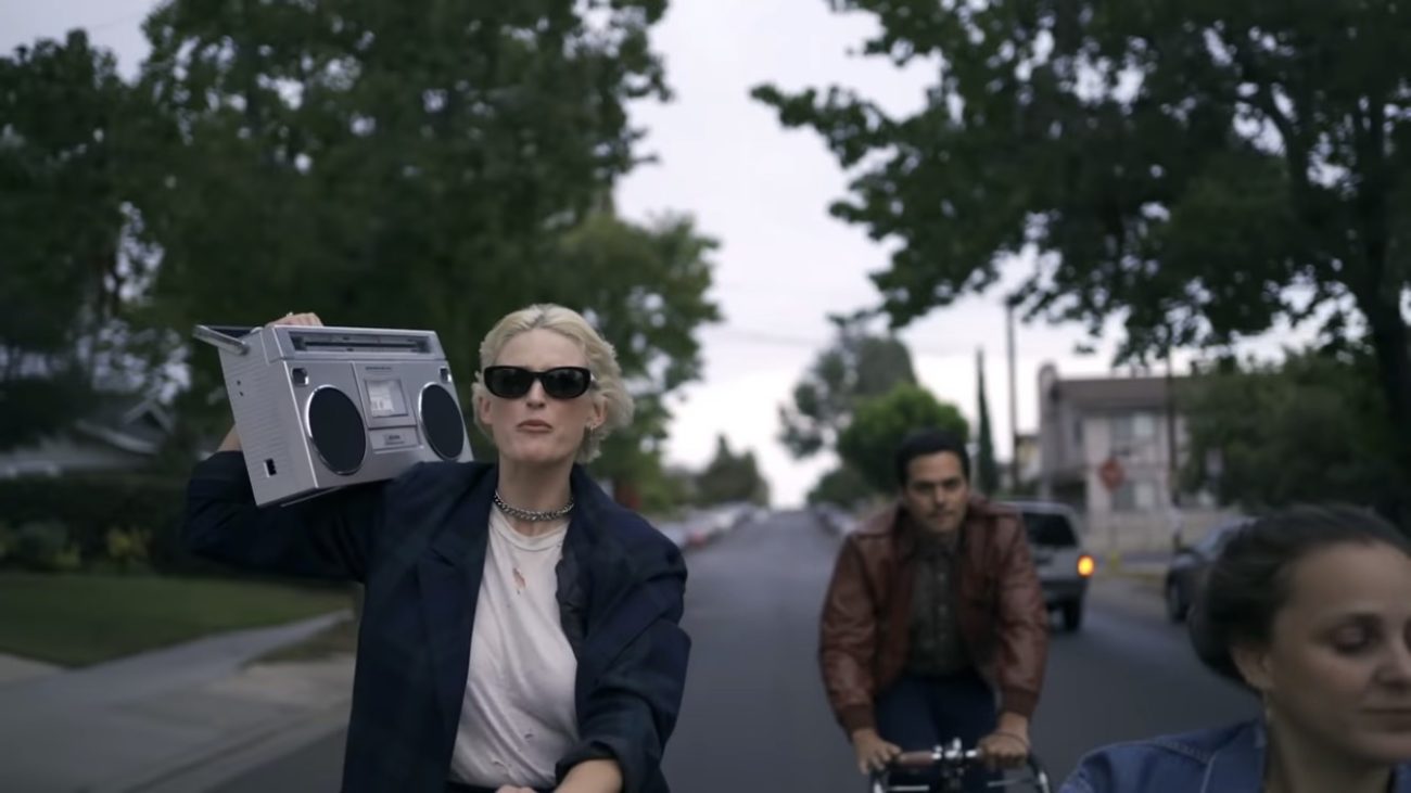 Members of Dead Sara ride bikes through suburban streets. Emily Armstrong is holding a boom box.
