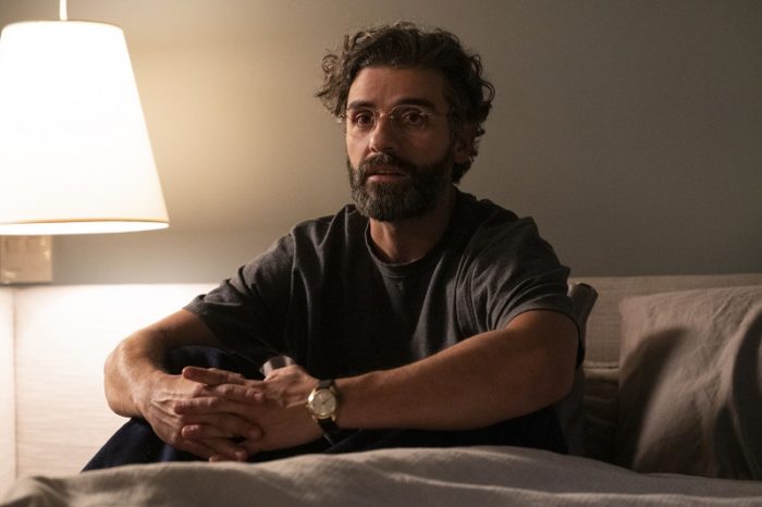 In this image from Scenes from a Marriage, Jonathan (Oscar Isaac( is depicted in bed, sitting up alert and looking towards the camera.