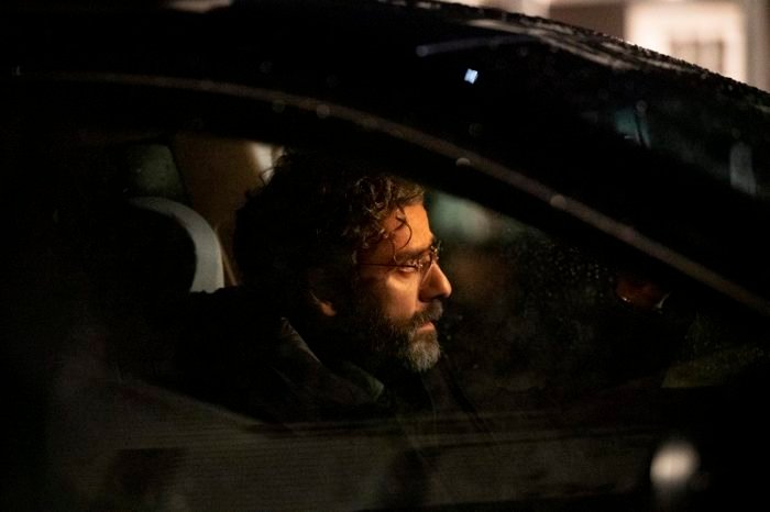Jonathan (Oscar Isaac) is depicted behind the wheel of his car, looking back into his rear-view mirror as he slowly drives away.