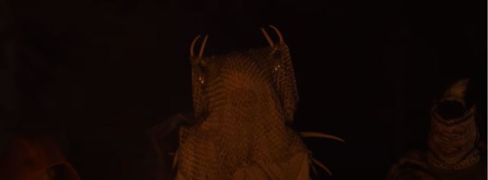 A figure with horns under a hood against a dark background