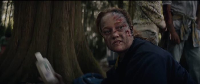 Van, with a bloodied face, holds a bottle of rubbing alcohol in the woods in Yellowjackets S1E2
