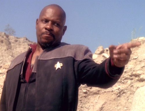 A disheveled looking Sisko is on a planet, pointing at someone, looking rather aggravated.
