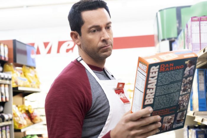 A man looks at the cover of a cereal box in a grocery store.